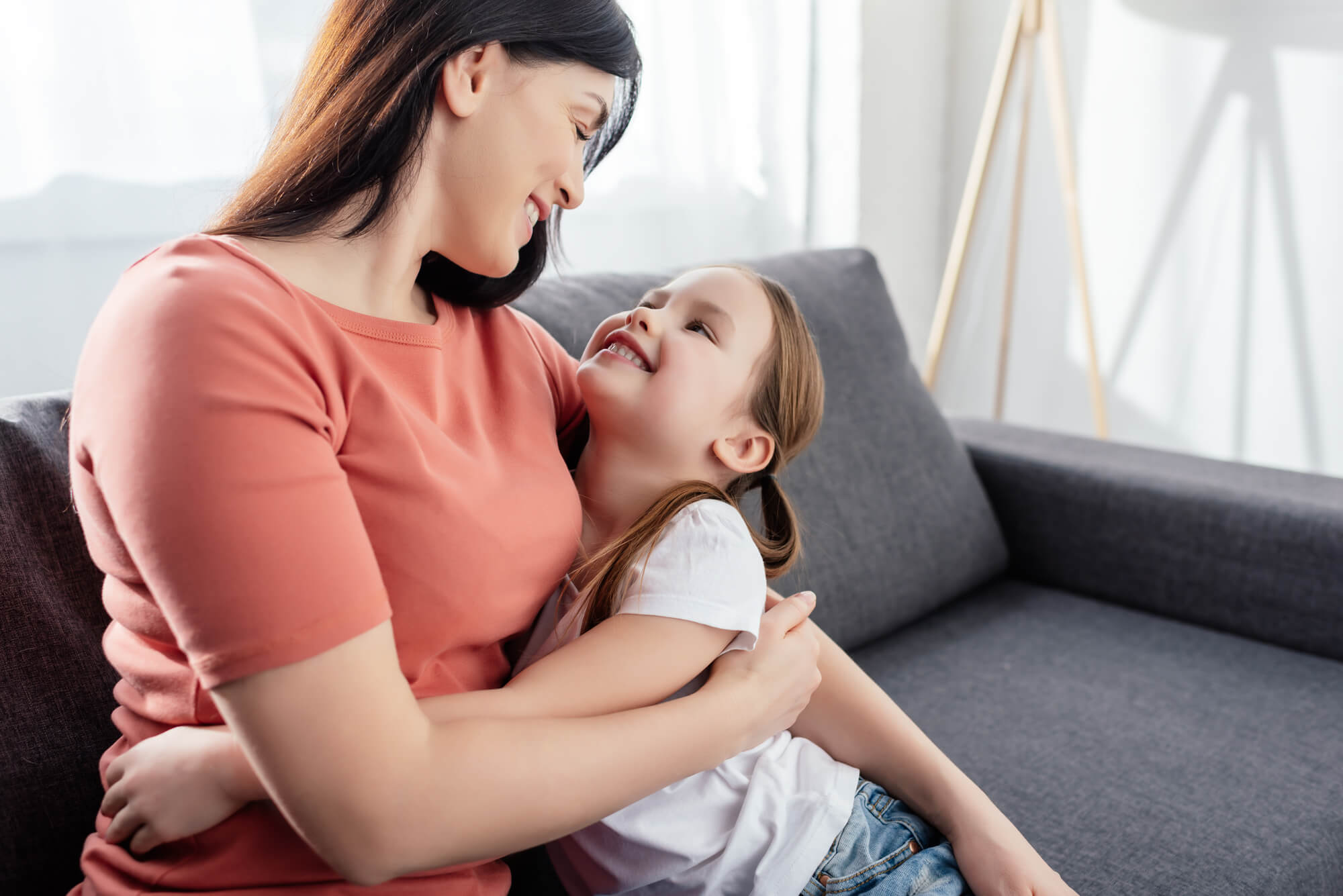 mom hugging daughter on a sofa